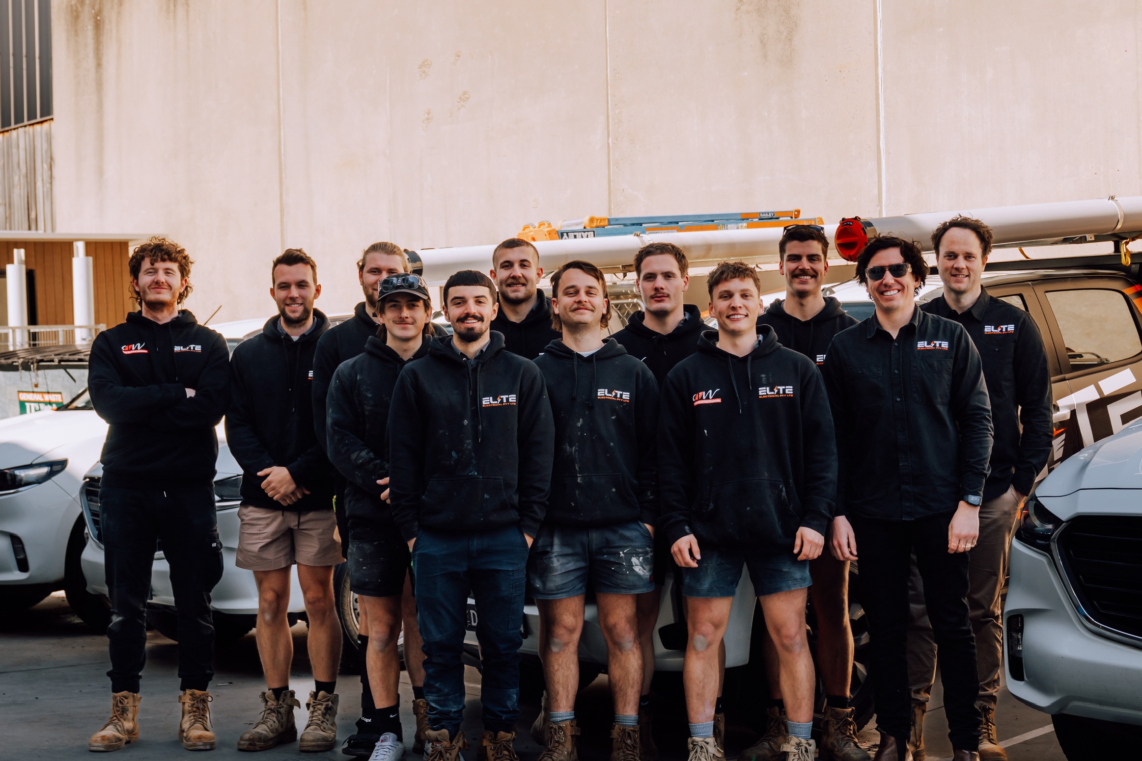 The Elite Electrical team together in front of their work vehicles